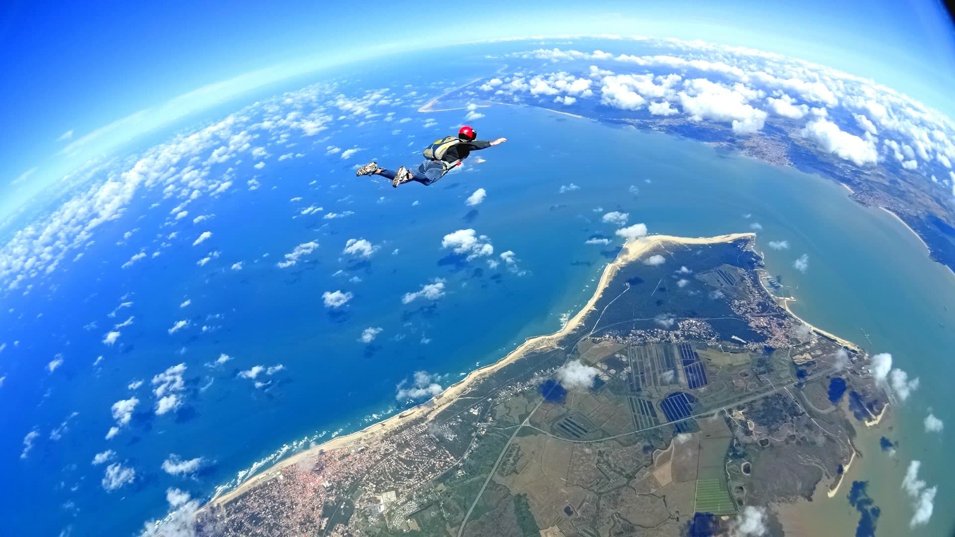 Photo d'Anthony, le propriétaire du site, pendant un saut en parachute, avec l'océan en arrière-plan